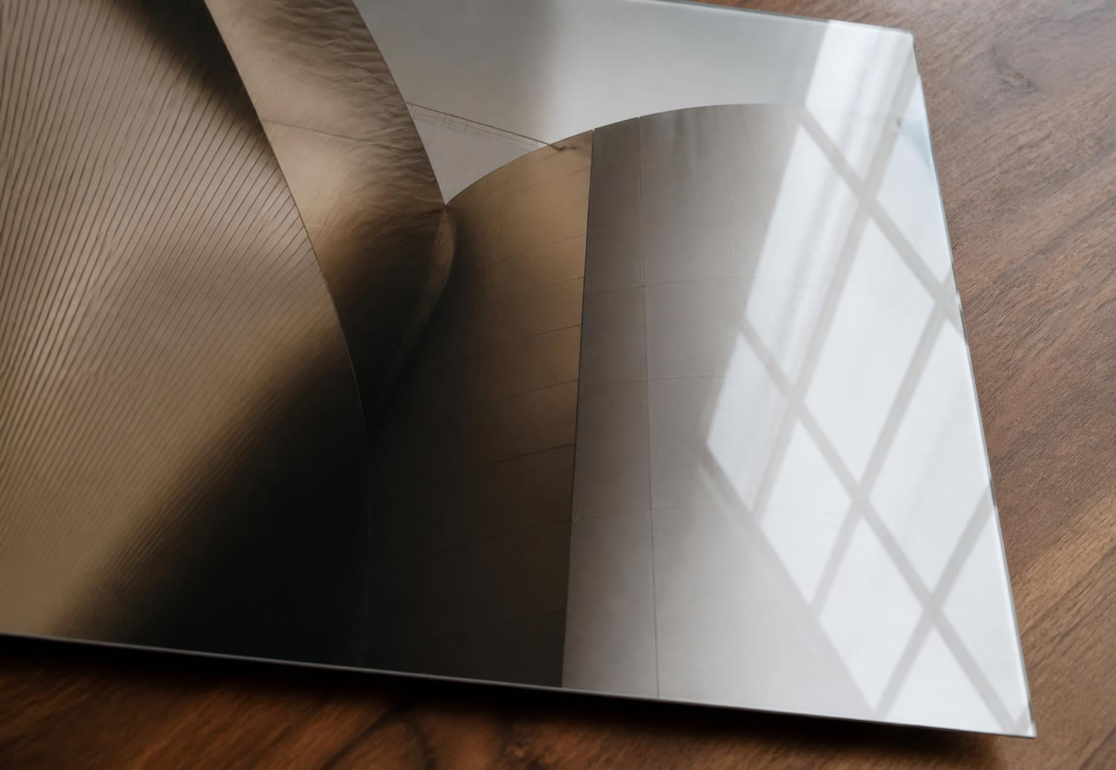 Close-up of a glossy metal print with soft window light reflecting across its surface