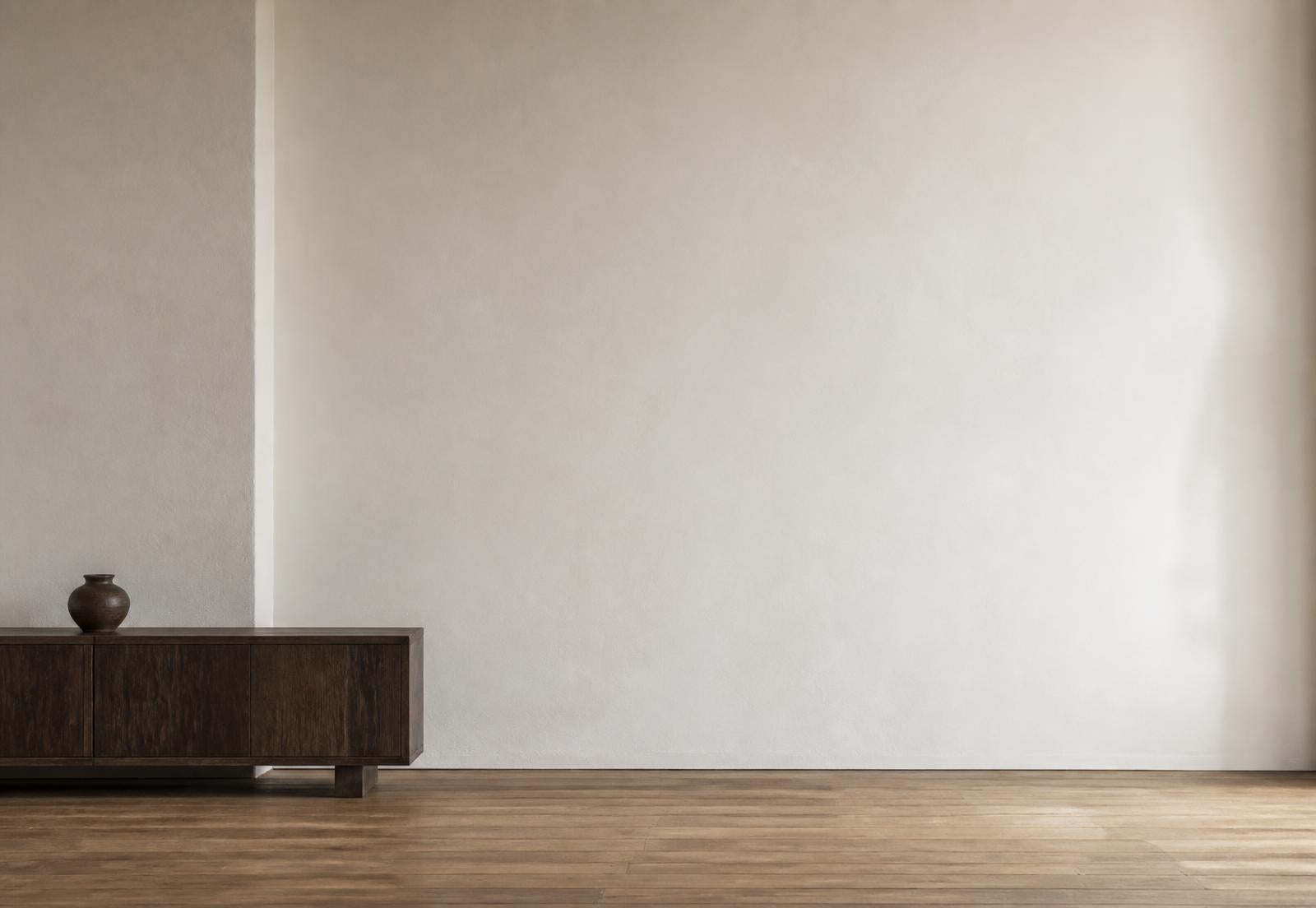 A plaster wall with a low dark wood console to one side, used as a fixed reference for print scale